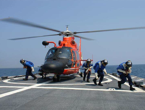 Crewmembers conduct flight deck operations with a MH-65 helicopter. Crewmembers conduct flight deck operations with a MH-65 helicopter.